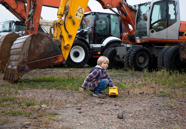 Menino Brincando Com Bulldozer Brinquedo Frente Várias Escavadoras Rodas Grandes — Fotografia de Stock
