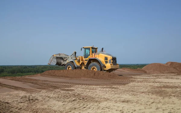 Bulldozer or loader move the earth at the construction site against the blue sky. Construction heavy equipment for earthworks. Commercial vehicle for construction site