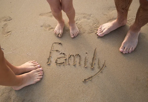 bare feet of family, father, mother and child on sandy beach. The inscription Family on the sand. Unity on vacation on the sea coast, holidays, pleasant moments to remember, spending time together