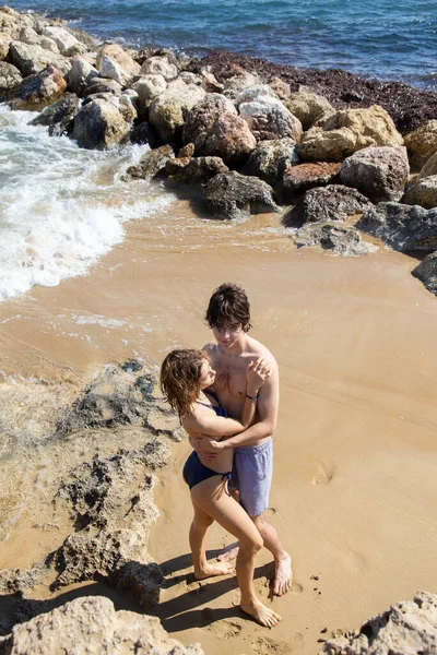 young man and woman about 20 years old, a couple in love, in full growth gently hugging on the beach. enjoyment of the moment, tender feelings, pleasant pastime. Valentine\'s Day together. Top view