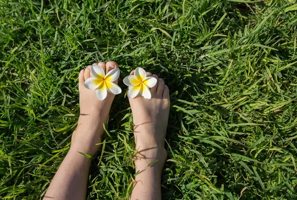 Child Bare Feet Lie Green Lawn Two Plumeria Flowers Toes — Stock Photo, Image