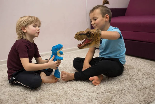 preschool boys play role playing games with dinosaur toys while sitting on rug. Communication with friends, friendship between brothers, entertainment for children, joyful childhood. selective focus.