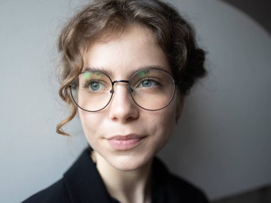 18-19 yaşlarında, liseli, üniversite öğrencisi bir kızın portresi. Gözlüklü hoş, zeki bir kadın. Düşünüyor, başka tarafa bakıyor. Gerçek insanlar, günlük hayat. Seçici odak