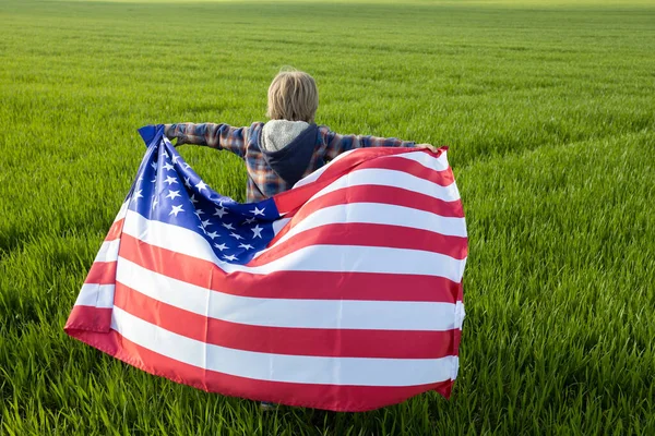 在一个无法辨认的孩子身后的绿草背景上 悬挂着美国国旗 独立日 美利坚合众国自由和独立的国家象征 — 图库照片
