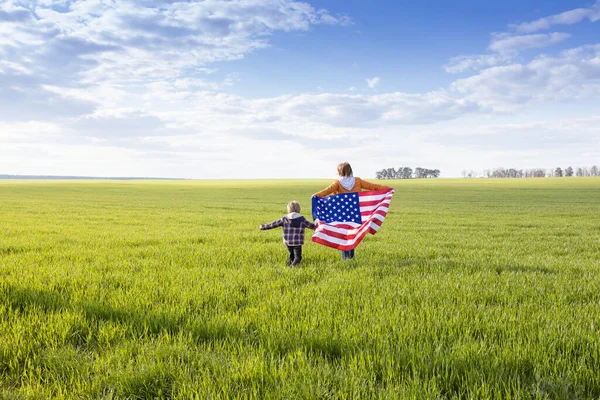 女人和孩子们背着美国国旗 在绿草上跑步很开心 这是爱国的节日 作为美国人的自豪和自由 美国庆祝7月4日 独立日 — 图库照片
