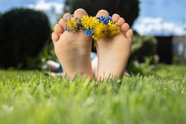 Gołe Stopy Dzieci Małym Wieńcem Kwiatów Leżą Zielonej Trawie Słoneczny — Zdjęcie stockowe