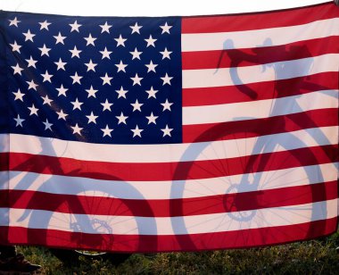 Çocuk ve yetişkin bisikletlerinin siluetleri büyük Amerika bayrağının arkasında arka planda. Amerika Birleşik Devletleri 'nin Bağımsızlık Günü. Bisiklet, seyahat, yaz tatili. boş zaman