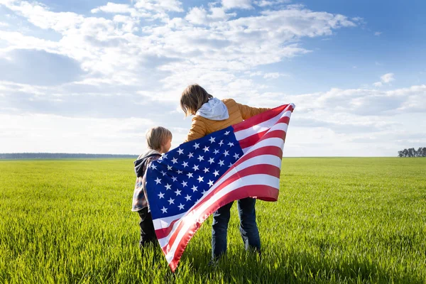 母亲和孩子 母亲的儿子站在草地上 背着美国的大旗 爱国假日 独立日 作为一个美国人感到自豪 民族意识 国家旅行 — 图库照片