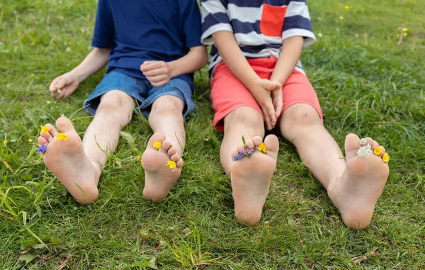 Босые Ноги Двух Детей Сидящих Лугу Маленькие Цветы Выделяются Среди — стоковое фото