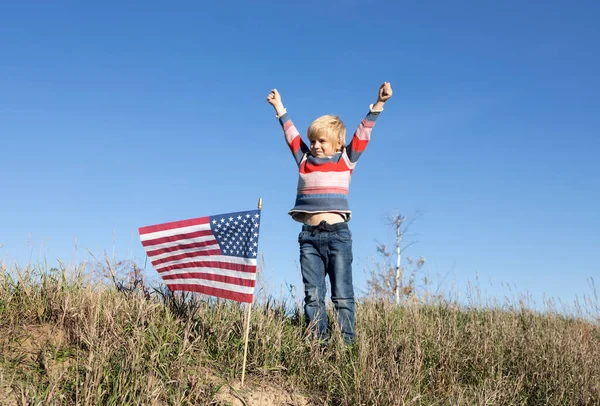 Хлопчик Гордо Підняв Руки Поблизу Стоїть Американський Прапор Зосередившись Прапорі — стокове фото