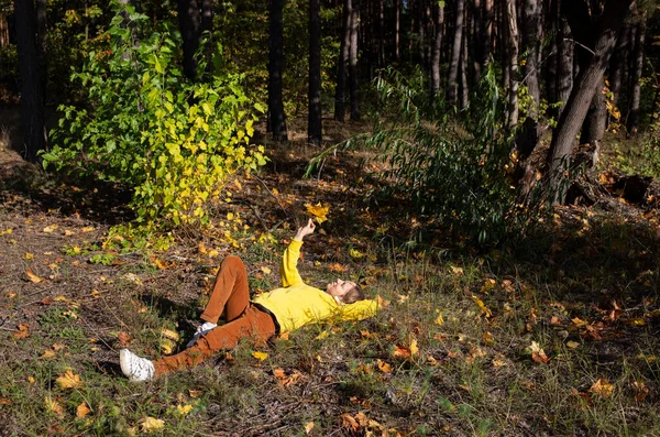 在一个温暖的阳光明媚的秋日 快乐的女人躺在落叶间的草地上 积极的气氛 与自然的统一 数码排毒 — 图库照片