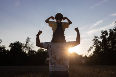 Gün batımında birlikte yürüyen baba ve oğul birliği. Arkadaş canlısı aile kavramı. İnsan çocuğunu omuzlarında taşır, güneşe karşı kahramanca güçlerini gösterirler. Eğlence eğlencesi, olumlu düşünce.