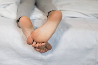 Bebek ayaklarının şirin resimleri. Bebeğin çıplak ayakları yatağın üzerinde, yakın plan. İyi sabahlar. Tatlı rüyalar. Rahat bir uyku, zevkle uyumak, çocuksu bir şefkat.