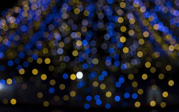 happy winter holidays. defocused garlands of glowing yellow and blue garland bulbs. Abstract festive background in colors of Ukrainian flag, bokeh. Stop the war . Dreams of peace in Ukraine