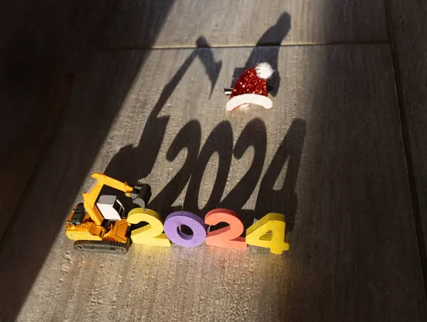 建設掘削機の玩具モデル 2024年の数字 サンタの帽子の対照的な影 年末年始のクリエイティブおめでとうございます 光と影の遊び 楽しみにして ストック写真