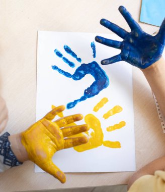 Ukrayna bayrağının sarı ve mavi renklerine boyanmış renkli çocuk el izleri. yaratıcı vatansever konsept. Ukraynalı çocuklar savaşa karşıdır. Ukrayna 'yı destekleyin. çocukluk