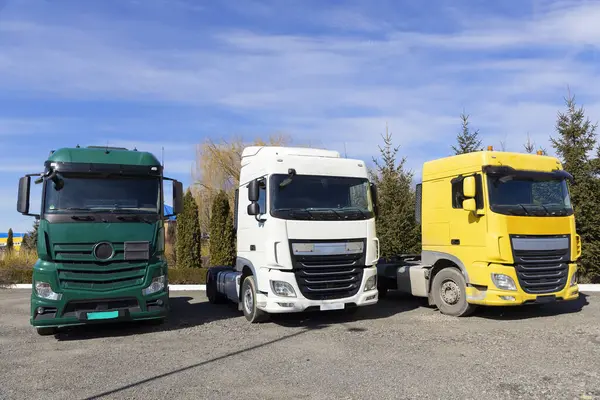 Three trucks parked in row on a sunny day . cabs of different colors of tractor-trailers. Commercial vehicles, advertising of cars for business transportation. Industrial machines for leasing