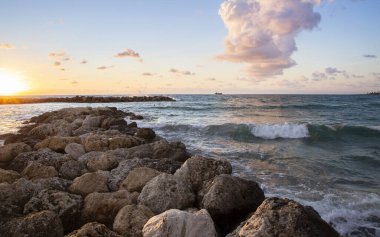 Denizin üzerinde gün batımı. Deniz manzarası. Merhaba tatil, tatil, seyahat. Dalgaların, güneşin, taşların, bulutların güzel birleşimi