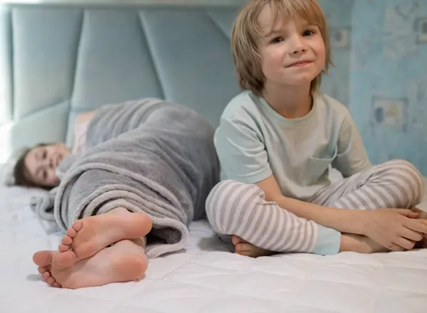 パジャマの2人の裸足の子供 兄弟と妹は 自宅でベッドで遊びます 子供の朝や夕方の家族は 甘やかしています 子供の元気な子供時代 居心地の良い休息 選択的な焦点 ストックフォト