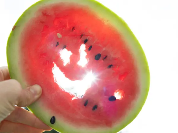 round piece of watermelon with a smile carved into it. Funny watermelon in backlight. Summer sunny mood. good mood, delicious vitamin-rich food