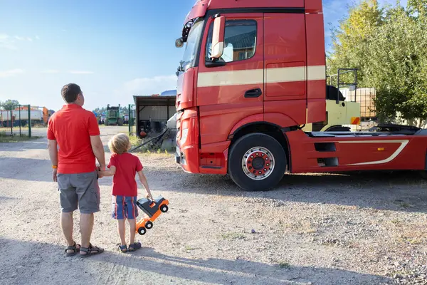 stock image boy and a man standing with their backs against the backdrop of the cab of a tractor-trailer examine the cars with interest. Spend the day with your son. The boy's interest in machines and their work