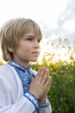 Ukrayna 'nın ulusal nakışlı tişörtlü çocuğu ellerini duaya bulayıp Tanrı' ya ve Ukrayna için zafer hayaline dönüyor. Savaşı durdurun.