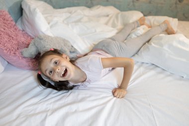 Komik kız 8 yaşında, büyük bir yatakta yatıyor. Çocukluk, pozitif atmosfer. Günaydın.