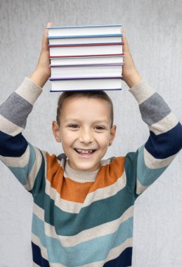 7-8 yaşlarında, elinde birkaç kitap tutan sevimli bir çocuğun yüzü. Komik eğitim reklamı. Okumakla ilgileniyorum. Kitap Günü. Okula geri dön.
