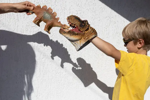 stock image Shadow theater. Mom and son are playing a dinosaur battle against a white wall. interesting contrasting shadows on the wall. ideas for games in the family, development of imagination.