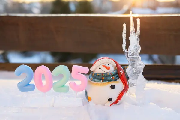 stock image large icicle and a cute souvenir snowman, numbers 2025 as home decorations for the Christmas holidays. Postcard with a festive mood for the winter holidays