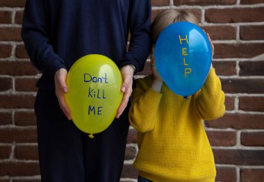 two unrecognizable people are holding blue and yellow balloons with text inscriptions, don't kill me, and help. Ukrainian children are asking to stop the war. Fear, despair, drawing attention clipart