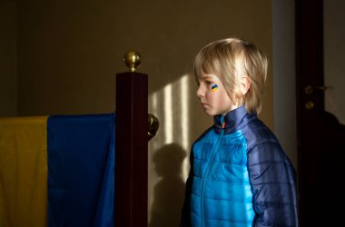 Yanağına sarı ve mavi bir kalp çizilmiş Ukraynalı üzgün bir çocuk, bir ışık şeridiyle işaretlenmiş. Savaştan ve Ukrayna vatandaşlarının üzüntüsünden dolayı. Savaşa karşı çocuklar