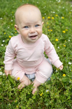 barefoot cute girl 6-7 months old sits on the grass. Focus on the eyes. Getting to know nature. positive child, awaken interest in the environment, the joy of childhood. Healthy happy children clipart