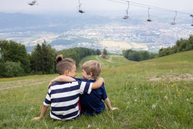 İki erkek arkadaş, sırtlarını tepede otururken birbirlerine sarılırlar. Kardeşler. Arkadaşlık, destek ve birlik kavramı. Dikiz aynası. Aktif eğlence, doğadan ilham. Yaz tatili