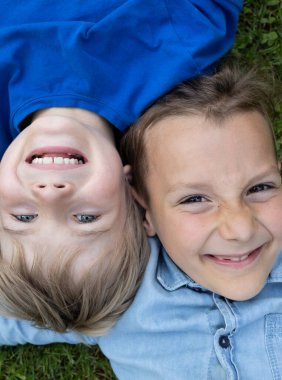 Çimlerin üzerinde yatan iki mutlu çocuğun yüzleri. Kaygısız neşeli bir çocukluk. Arkadaşlık ve pozitiflik kavramı. Keyfin yerinde. Üst görünüm