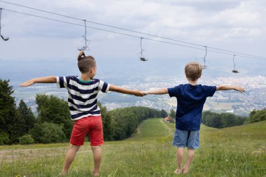Tanımlanamayan iki çocuk el ele tutuşup, doğa yürüyüşü yaparken şehre bakıyorlar. Dijital detoks, hafta sonları doğa, ailenle yürüyüş. Toprak enerjisi, arkadaşlık kavramı