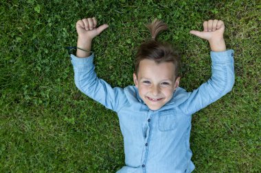 Çimlerin üzerinde yatan 8 yaşında tatlı bir çocuk. Çocukluk sevinci, pozitiftir. Merhaba yaz, doğanın enerjisi. Yaz havası, çocukluk hayalleri, kaygısız neşeli bir çocukluk. Üst Manzara. Elle yapılan bir jest gibi.