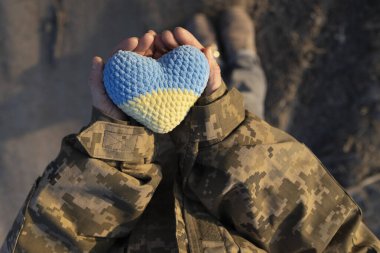 Ukrayna askeri elinde örülmüş sarı ve mavi bir kalp tutuyor. Ukrayna 'nın yanında dur. Ukrayna 'nın Koruyucu Günü. Bağımsızlık Günü. Ukrayna 'nın silahlı kuvvetlerine güven. Anavatanı sevmek