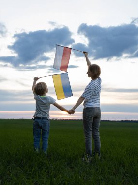 Çocuk ve kadın el ele tutuşup Ukrayna ve Polonya bayraklarını kaldırıyorlar. Avrupa birliği ve Ukrayna 'ya destek. Uluslararası dostluk ve işbirliği. Göçmen sorunları