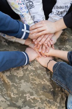 Askeri piksel üniformasının arka planında birbirini tutan bir çift çocuk eli. Ukrayna 'ya destek. Ukrayna Günü 'nün savunucusu. Bağımsızlık Günü. İnanç ve Takdir Silahlı Kuvvetler