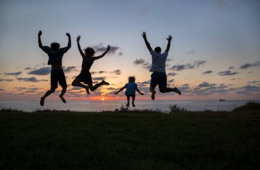 Gün batımında deniz kenarında sevinçle hoplayıp zıplayan 4 kişinin silueti. Özgürlük kavramı, mutluluk. - Evet. Enerji, gençlik, sağlıklı yaşam tarzı, mutlu gün