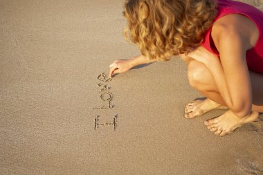 Yalınayak genç kız deniz kıyısında otururken parmaklarıyla kuma sevdiğim kelimeleri yazıyor. Aşık olma, rahatlama, yaz havası, tatil kavramı. Keyifle seyahat et. Dijital detoks