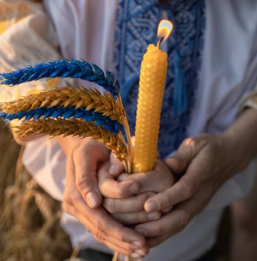İşlemeli Ukrayna gömleği, buğday başakları, buğday tarlasında sarı-maviye boyanmış kadın ve çocukların ellerinde yanan mum. Holodomor sırasında ölenlerin anısına tahıl ve ateş.