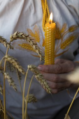 Gün batımında buğday başakları arasında dişilerin ellerinde yanan mum. 1932-1933 yılları arasında Ukrayna 'da yaşanan Holodomor trajedisinin anısına konsept fotoğraf. Ukrayna yanıyor, savaşı durdurun.