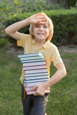 Sekiz yaşındaki neşeli, şaşkın bir çocuk elinde koca bir yığın kitap tutuyor. Okuma beklentisiyle. Kitap günü. Tatilde okunacak kitapların listesi. Yeni kitaplar al. Dijital detoks