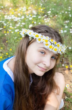 Parktaki papatya çelenginde 12 yaşında sevimli gülümseyen bir kızın portresi. Anın tadını çıkar, pozitif ol. Neşeli bir yaz. Gençlik sevinci.