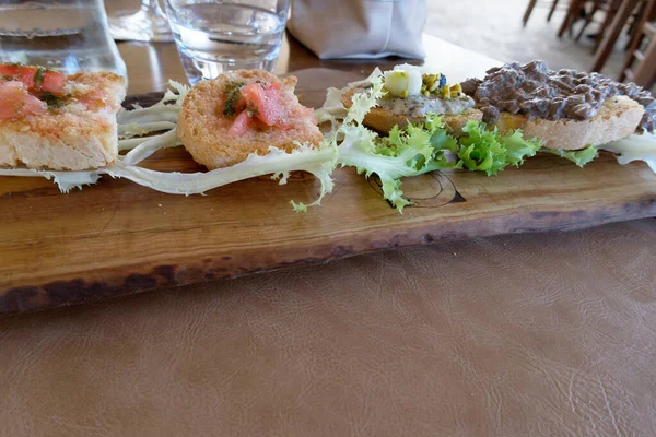 stock image Typical rustic tuscan appetizer with meat and tomatoes crostini on a wooden tray . Italian starter