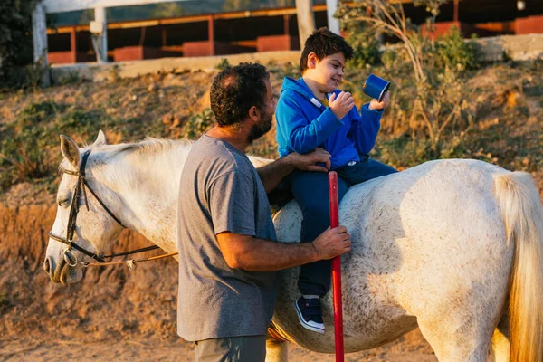 Disabled child doing mobility exercise during an equine therapy session using a horse