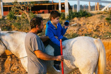 Child with disabilities having an equine therapy session with a physiotherapist. People with disabilities.