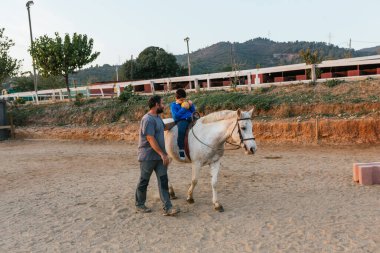 Boy with a disability doing exercises during an equine therapy session. People with disabilities and equine therapy concept.